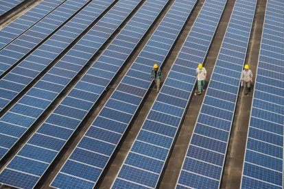 Unos trabajadores comprueban los paneles solares de una central fotovoltaica en el tejado de una fábrica del condado de Changxing, en la provincia de Zhejiang, al este de China.